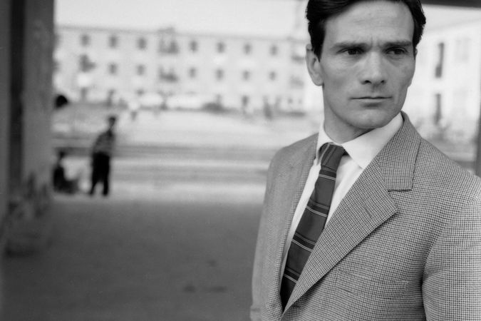 Pasolini sullo sfondo dei palazzi della borgata 