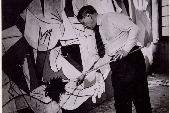 Picasso in piedi mentre lavora all'opera Guernica