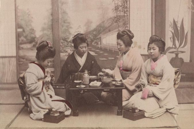 Gruppo di donne giapponesi in kimono attorno a un tavolo da té imbandito